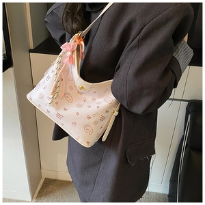 Detalle de bolso de hombro blanco con estampado de dibujos, cadena de color y lazo de seda