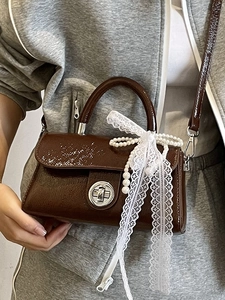 Elegant dark brown patent leather crossbody bag with lace bow and pearl chain detail