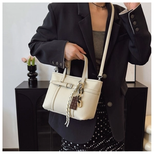 Close-up of cream lychee texture leather bucket bag with chocolate charm and silver buckle