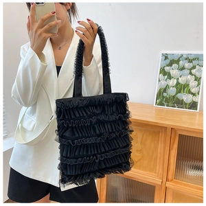 Détail du sac cabas noir à volants en mesh associé à un blazer blanc contrasté