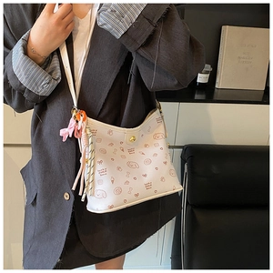 Detalle de bolso bandolera de cuero blanco con estampados de dibujos y colgantes tejidos
