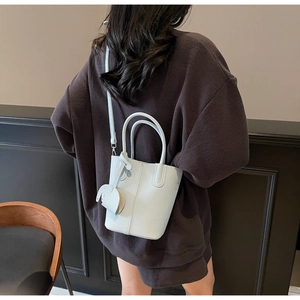 Borsa a secchiello azzurra con motivo litchi e ciondolo a elefante indossata da modella