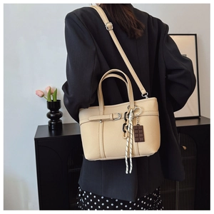 Detail of beige lychee texture leather bucket bag with silver buckle and chocolate charm