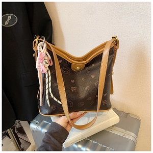 Detalle del bolso de hombro marrón con estampados bonitos y colgante de lazo rosa