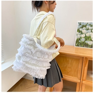 Sac fourre-tout en toile blanche à volants en maille porté par un mannequin en intérieur