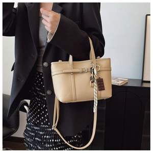 Detail of apricot bucket bag featuring lychee texture, silk scarf, and crossbody strap