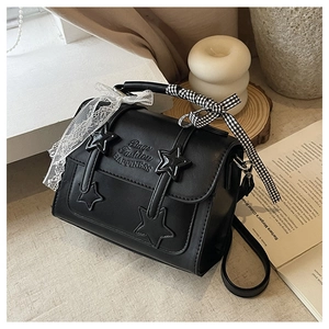 Detail of black star-patterned square handbag with lace and checkered bow accents
