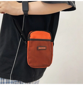 Detail of orange nylon mini crossbody bag with black mesh pocket and adjustable strap