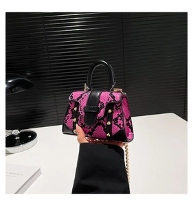 Mini-Handtasche mit rosa Schlangenhautmuster und Goldnieten in der Hand zur Größenansicht