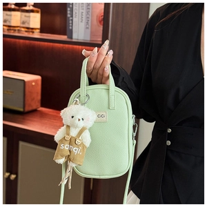 Détail du mini sac vert menthe avec pendentif ours en peluche et texture grainée