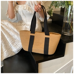 Detalle de bolso tote de paja tejido a mano con asas negras y patrones de textura rica