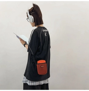 Detail view of mini crossbody phone bag in orange with mesh pocket and brand logo