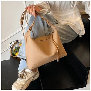Detail of light brown lychee grain leather tote bag with stylish woven knot pendant