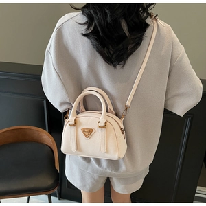 Detail view of cream white pebbled leather Boston bag worn by a model in a minimalist room