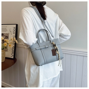 Lifestyle view of light gray lychee grain bucket bag with charms and a shoulder strap