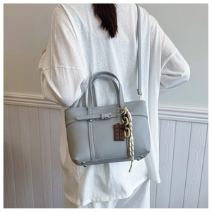 Back view of a model wearing a light grey litchi grain bucket bag with chain charms