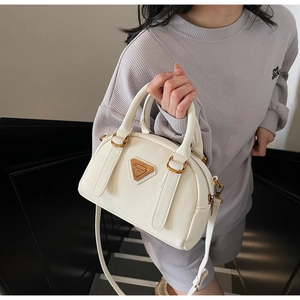 White lychee leather Boston bag with gold hardware and removable shoulder strap worn by model