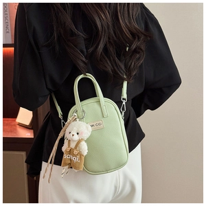 Détail du mini sac vert clair texture litchi avec porte-clés ours en peluche