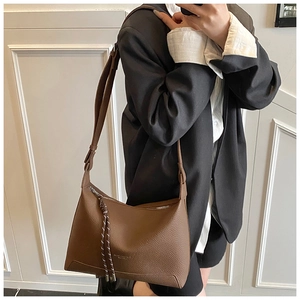 Close-up of brown litchi pattern leather tote bag with braided zipper puller and strap