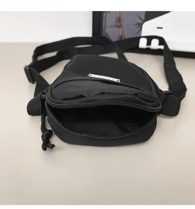 Detail view of black nylon mini crossbody bag with double zipper pockets and interior space