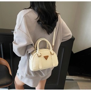 Detail of creamy white boston bag with lychee texture and metallic triangular logo