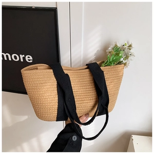 Detalle del bolso de paja trenzada con asas de lona negra y decoración floral