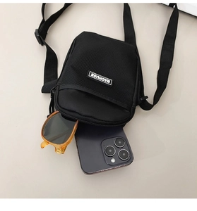 Macro detail of black nylon crossbody bag showing the logo patch and mesh fabric