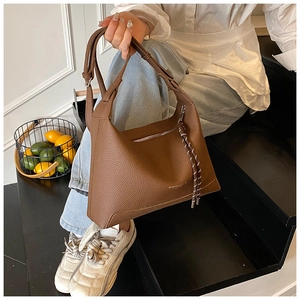 Detail of a dark brown pebble grain leather hobo bag with adjustable strap and tassels