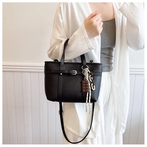 Detail of black lychee grain bucket bag with creative charms and silver buckle decor