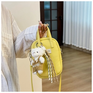 Détail du mini sac jaune en cuir grainé avec logo CiCi et charmant ours en peluche