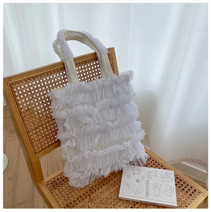 Détail d'un sac cabas blanc en mesh à volants avec dentelle sur une chaise en bois