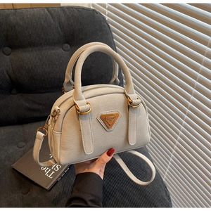 Detail of lychee pattern leather Boston bag with vintage gold triangular hardware