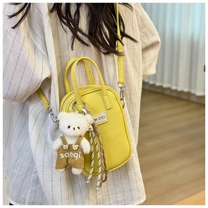 Mini sac bandoulière jaune vif avec texture litchi et charmant ours en peluche sur modèle