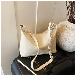 Detail of cream tote bag featuring premium lychee texture leather and woven zipper puller