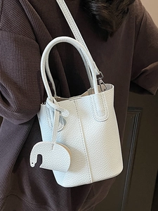 Borsa a secchiello minimalista in pelle bianca con manici e ciondolo a elefante