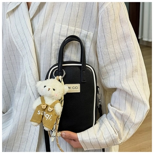 Détail du sac bandoulière contrasté avec texture litchi et pendentif ours mignon