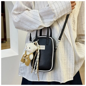 Détail du sac à bandoulière noir avec bordure blanche et pendentif ours en peluche mignon