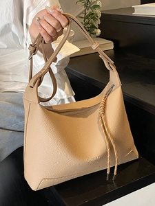 Minimalist lychee pattern tote bag in beige leather with an adjustable strap on model