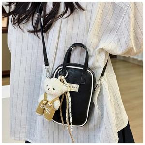 Sac bandoulière noir texture litchi avec passepoil blanc et breloque ours en peluche