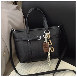 Detail of black lychee grain bucket bag with silver buckle and chocolate pendant decor