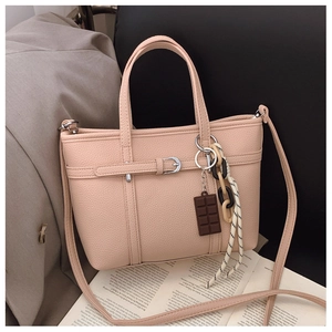 Detail view of beige lychee texture bucket bag with decorative buckle and chocolate charm