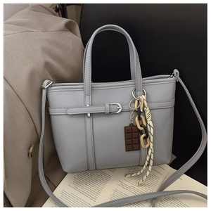 Detail of grey bucket bag with lychee texture, buckle strap and decorative charms