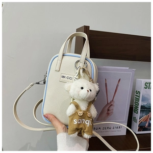 Détail du sac bandoulière motif litchi avec breloque ours et logo MK en métal