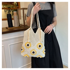 Gros plan d'un sac cabas tissé avec des tournesols jaunes et un gland dans un café