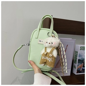 Détail du mini sac vert clair texture litchi avec charm ourson et finitions argentées