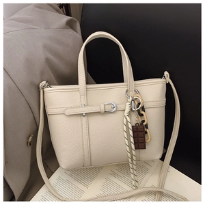 Detail shot of cream bucket bag showing lychee grain leather texture and charms