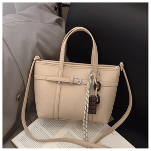 Detail of beige bucket bag in lychee texture with woven rope and chocolate charm