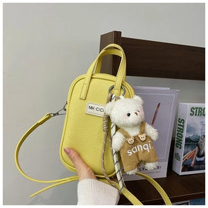 Gros plan détaillé du sac en cuir jaune motif litchi avec un charmant petit ours