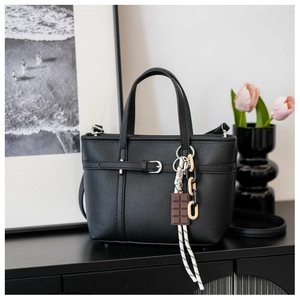 Detail of black lychee grain bucket bag featuring a belt buckle and chocolate pendant decor