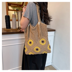 Détail du sac cabas beige tissé à la main avec motifs tournesols et décor de glands